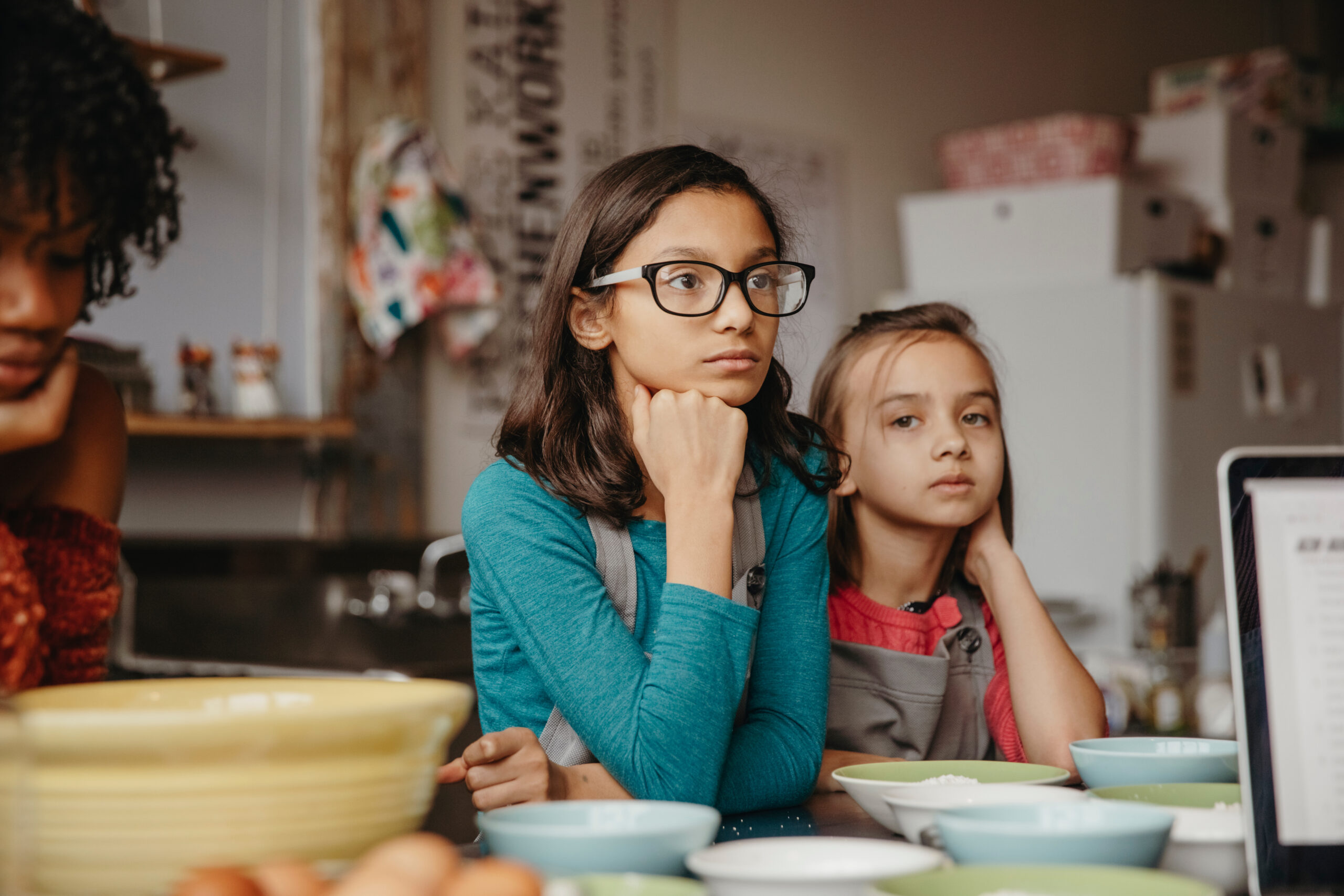 Portrait of girl standing with thoughtful friend standing by food in cooking class